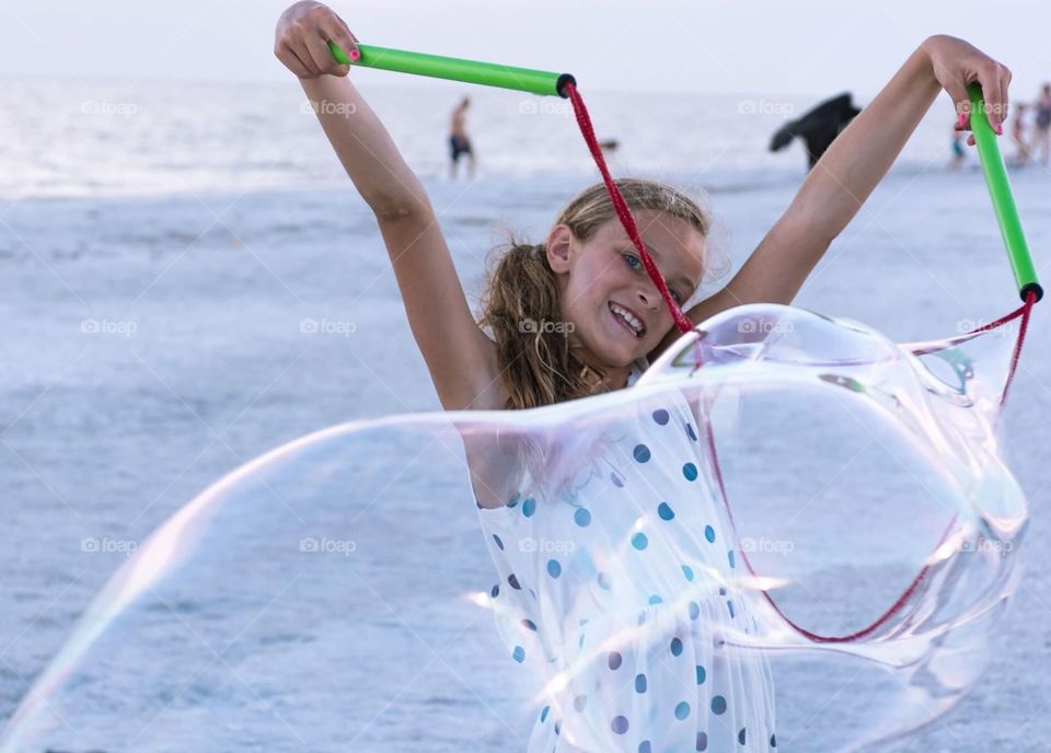 Girl has fun at beach with bubbles in summer 