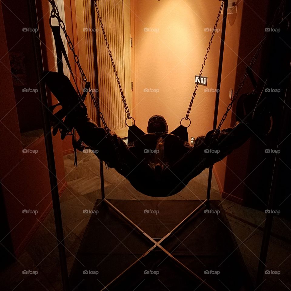 person in a bdsm suspension frame with swing