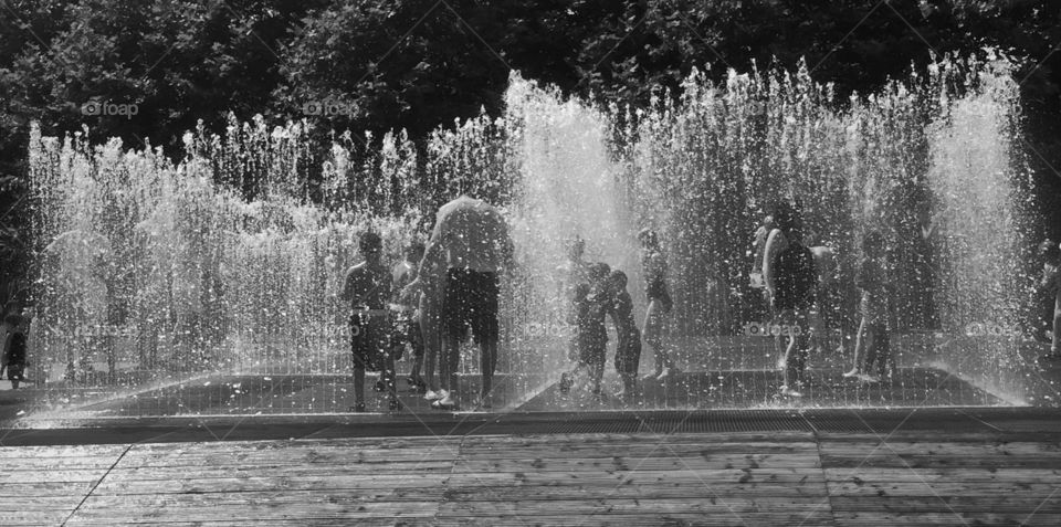 People play on a water fountain in a hot summer day 
