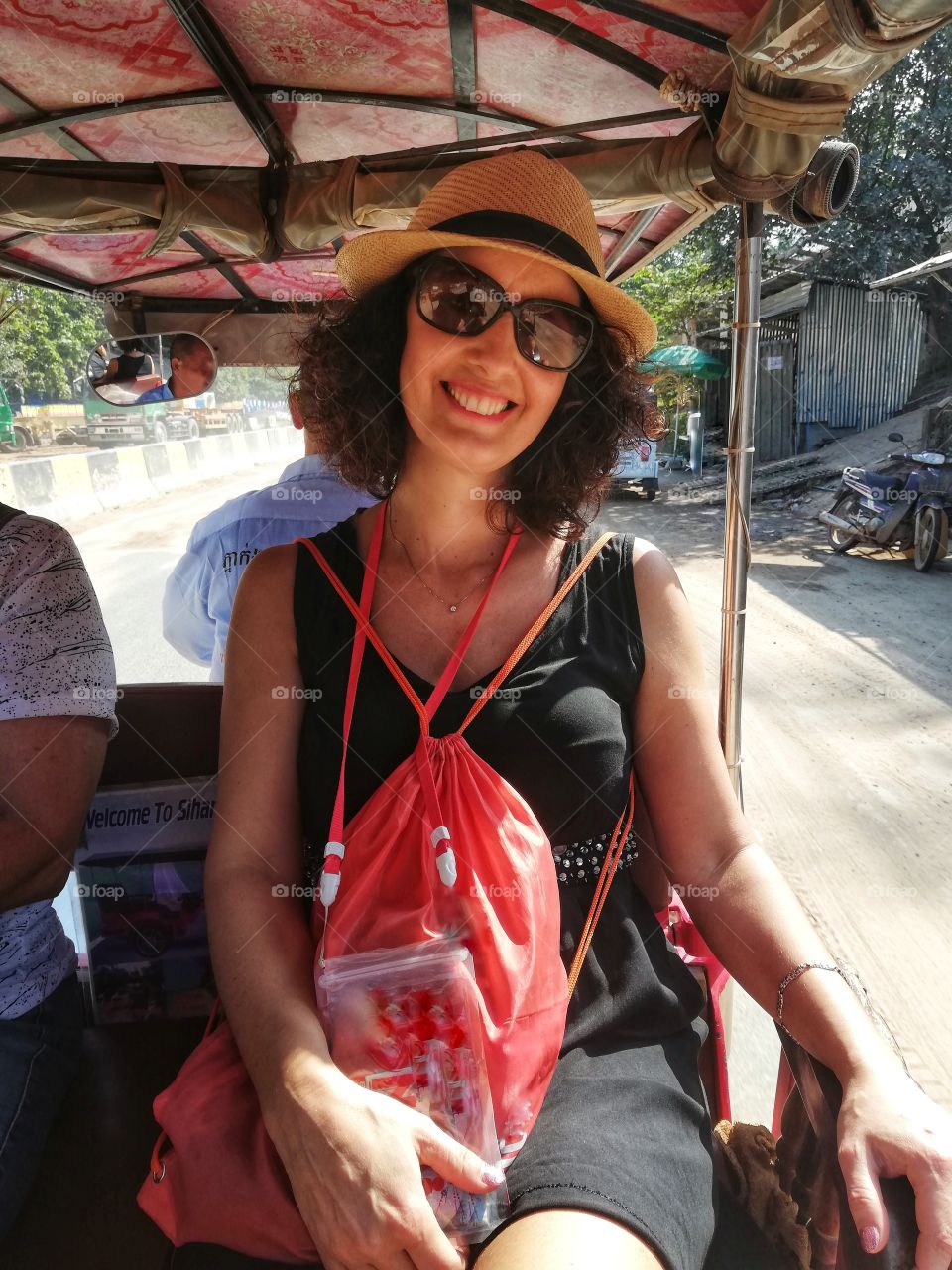 smiling woman on a three-wheeler on the Cambodian streets with friends