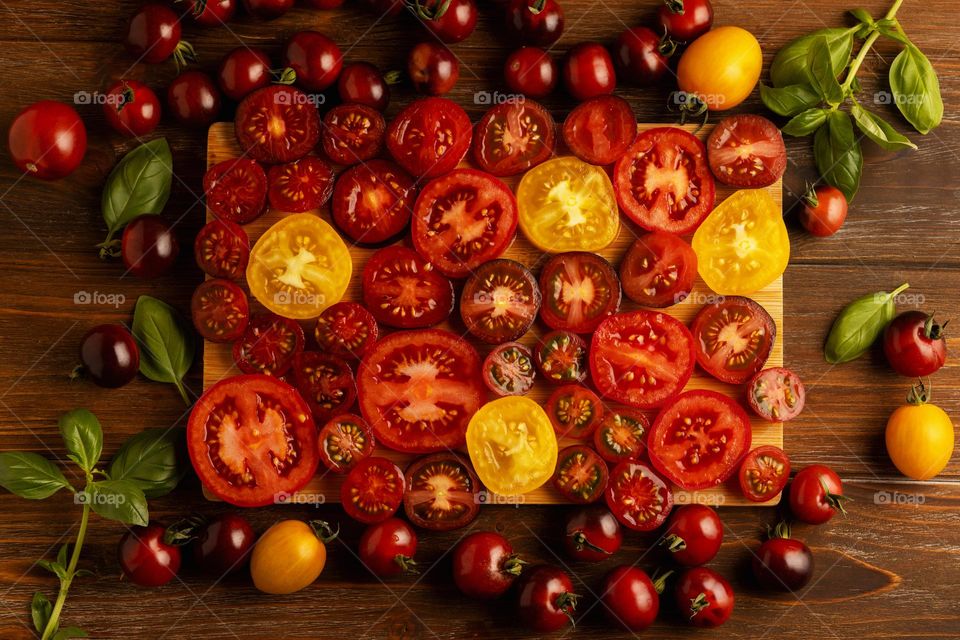 Composition of different tomatoes, slices of red and yellow tomatoes on a wooden board