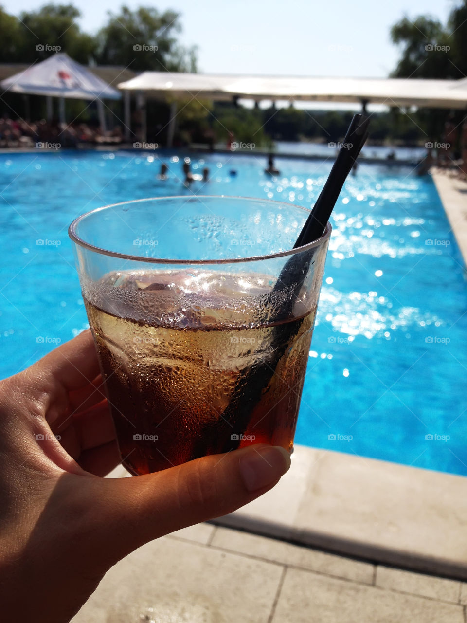 Enjoying the last summer days with a glass of cola by the swimming pool 