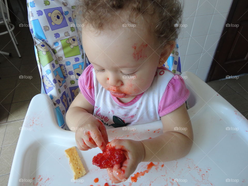 Baby sitting in high chair smashing food