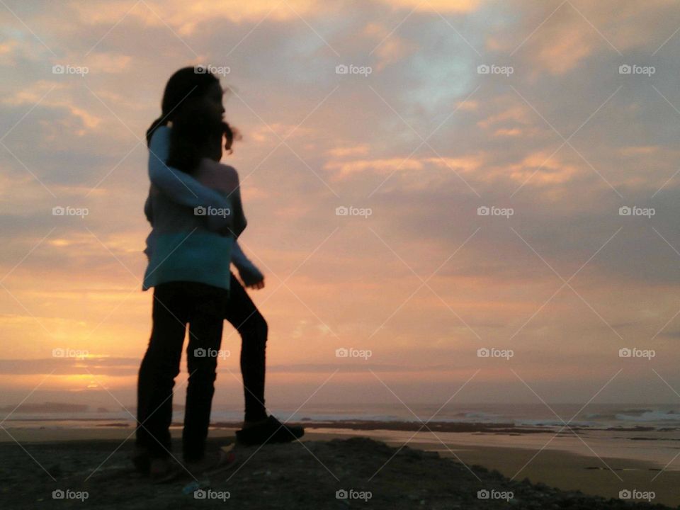 Two girlfriends standing against magic sunset at essaouira city in Morocco.