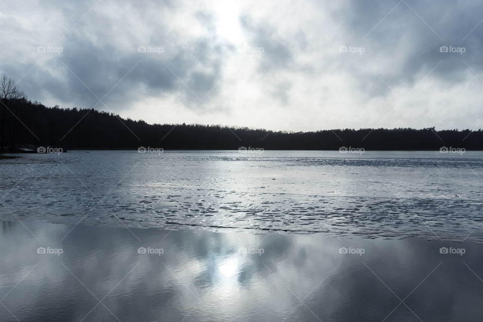 Cloud reflections in partly ice covered lake on a cold winter day 