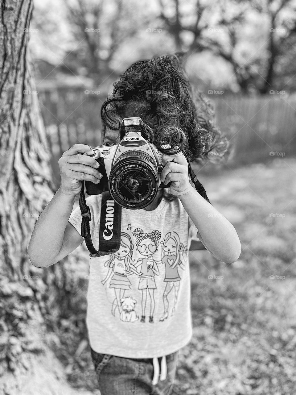 Toddler girl focuses camera, toddler takes picture with Canon, black and white portrait of toddler