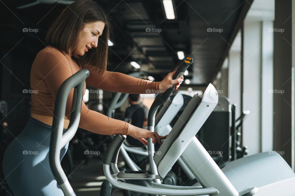 Young brunette woman training her muscles in the fitness club gym