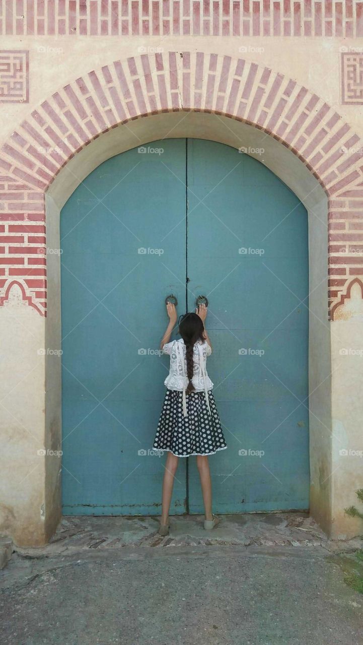 A small girl againt an ancient door.