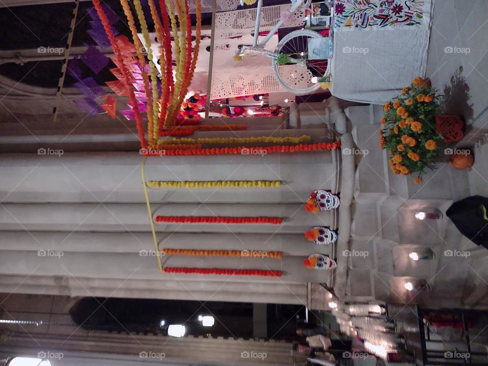 Chains of paper flowers, a display of paper skulls, and some potted marigolds are among the decorations for Day of the Dead