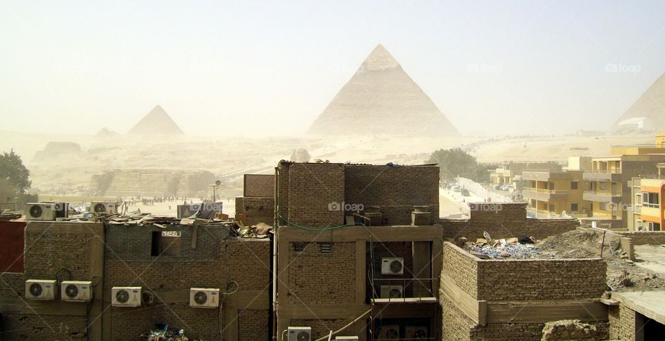 Modern day Cairo on the outskirts of the pyramids with a strong wind kicking up the sand