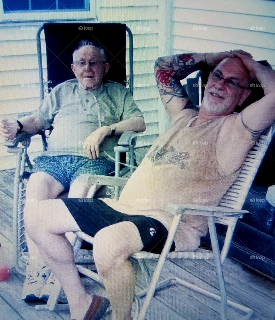 In-law men visiting & laughing together outside in summertime.