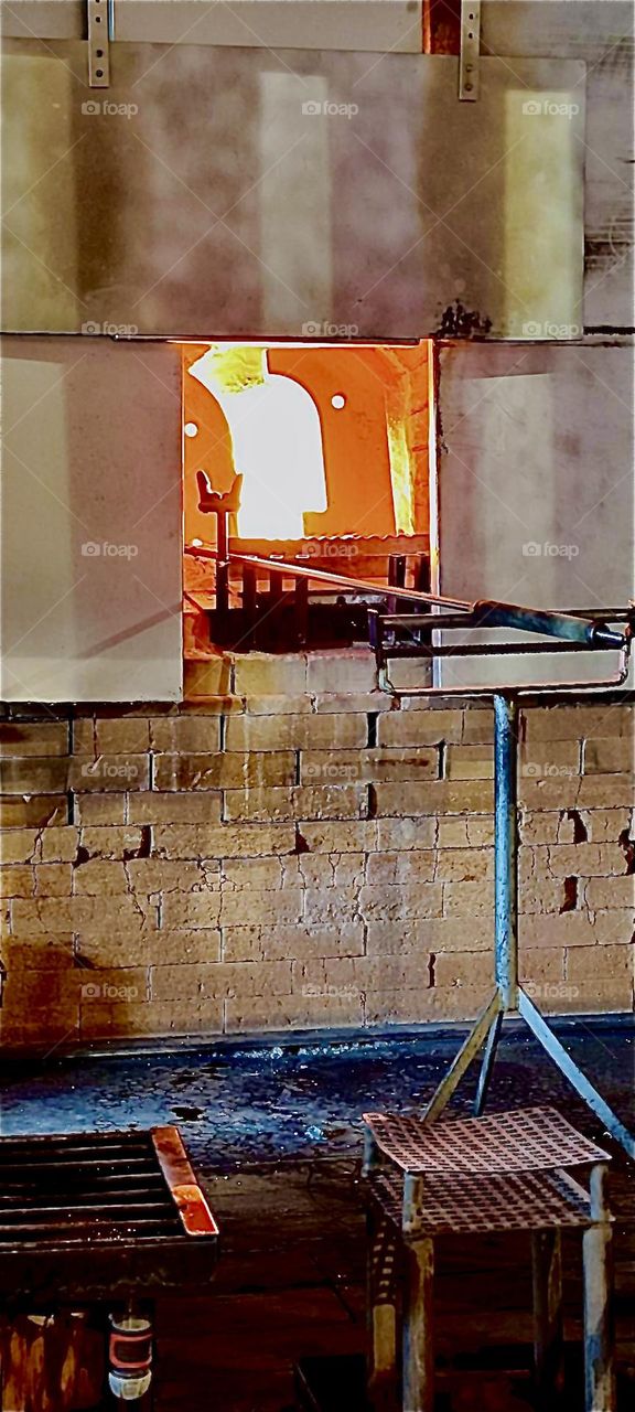 The temperature to turn glass into a workable substance is rather high. This furnace is “Freyung”, Bavaria, Germany can demonstrate just how hot it really is in there by showing the flames through the open front door. 2023. Hypnotic Productions