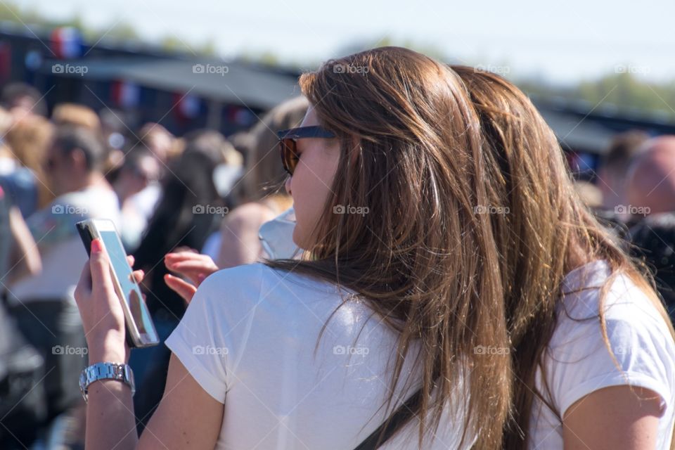 Two girl looking at a mobile phone while being on a festival 