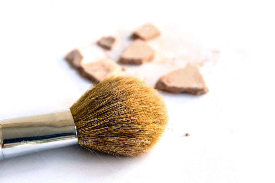 Makeup brush with crushed foundation on the background