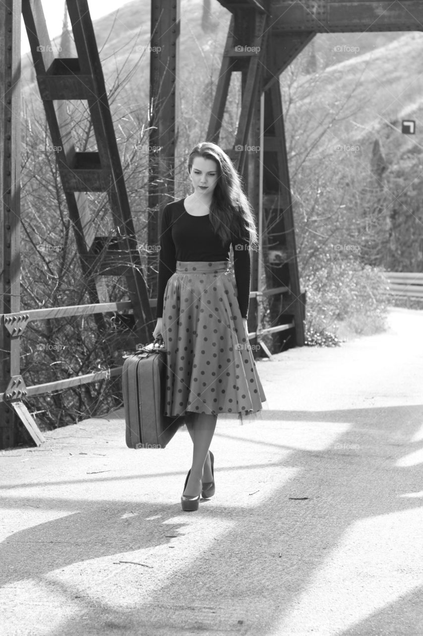 Young woman with suitcase walking on bridge