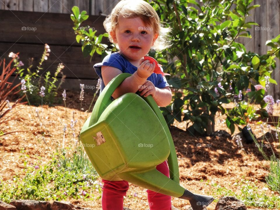 Girl With Watering Pail. Little Girl In The Garden
