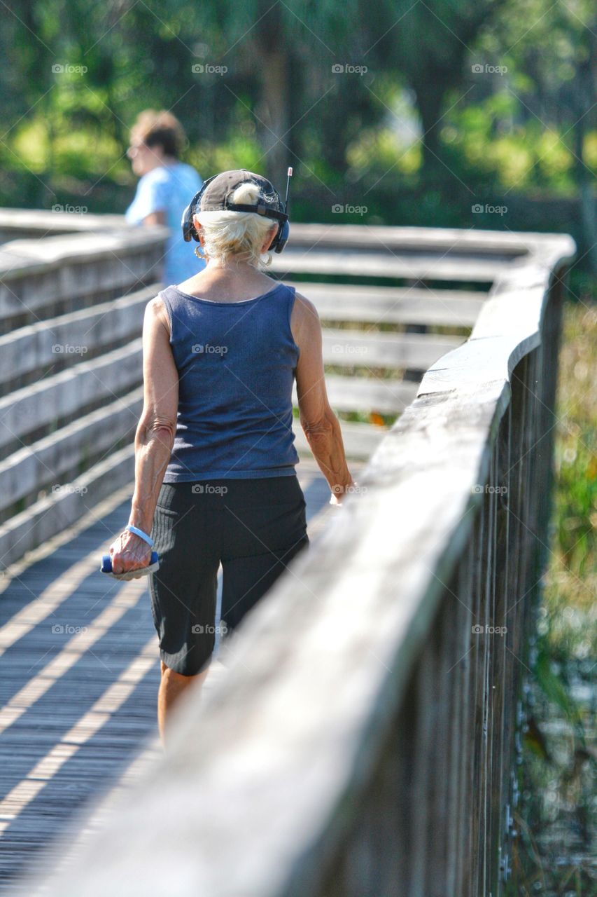 Elderly from behind. A walking workout along a scenic boardwalk in Florida.   