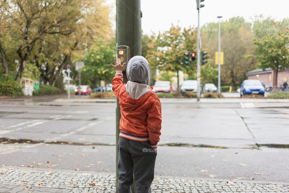 Boy pushing traffic lights. Young kid pressing button of traffic light in big city