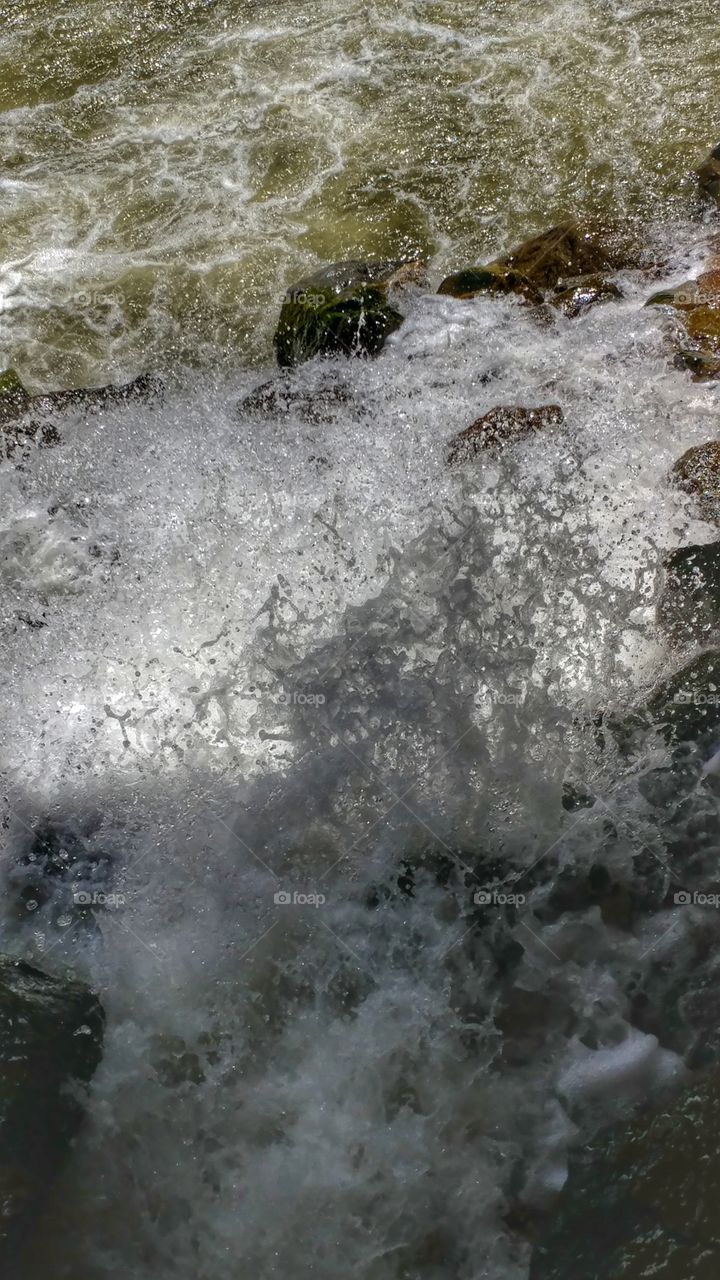Swirling, foaming rapids fight their way down a Colorado canyon on the spring time.