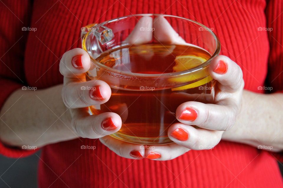 cup of tea in the female hands red manicure, cozy winter