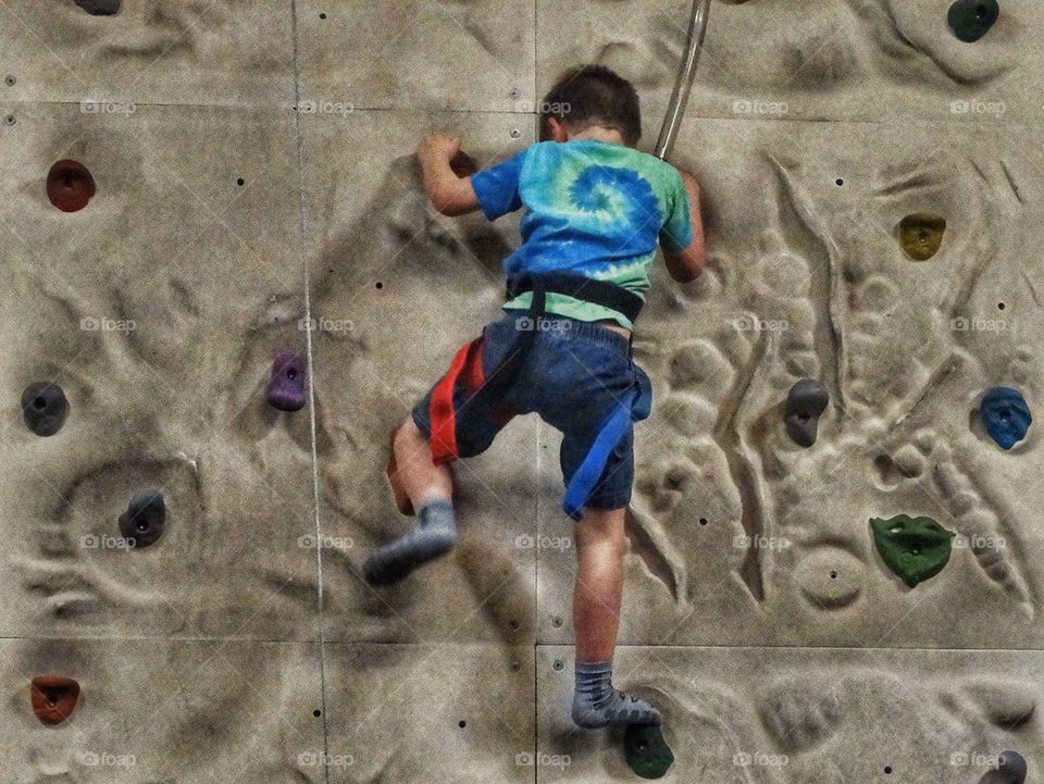 Young Boy Bouldering. Boy Climbing A Rock Wall
