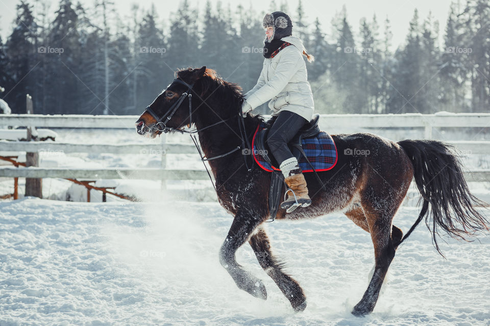 Teenage girl horseback jumping at cold winter day 