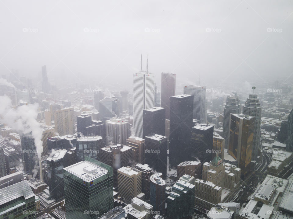 Toronto, Canada snowfall panoramic city view from CN tower observation deck. Cold Day with bad weather and white snow on the streets and skyscrapers of the Canadian capital.