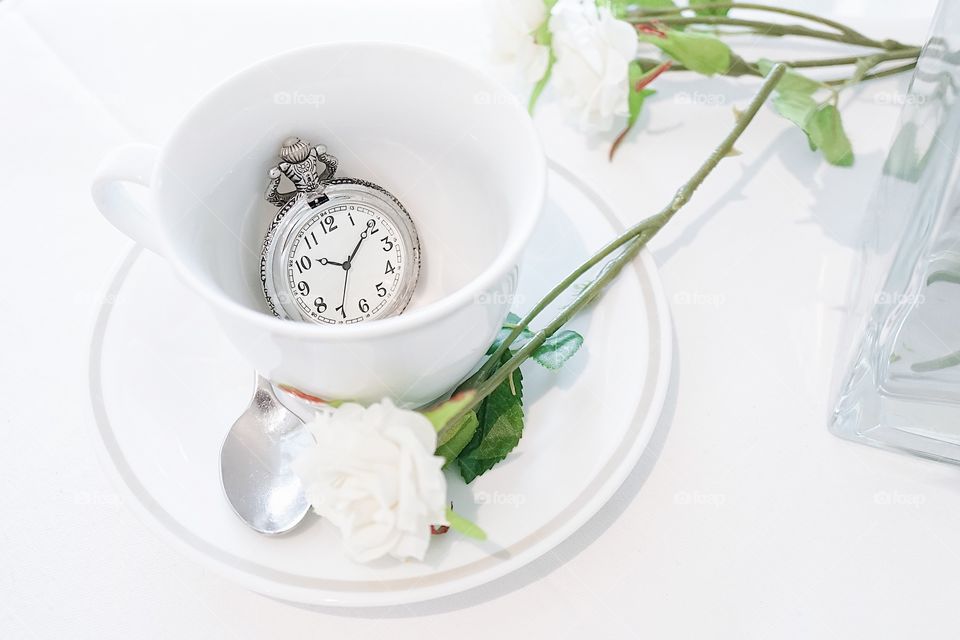 Vintage pocket watch. A closed up of a teacup with antique pocket watch inside. Tea break and tea time concept. Window light.