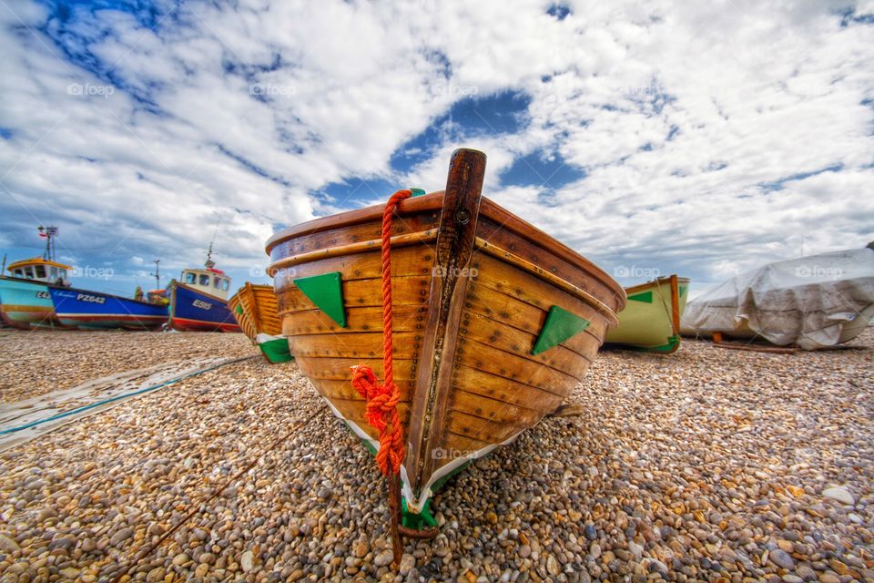 Beached Fishing Boats. A wooden fishing bits sitting centrally on a pebble beach surrounded by others.