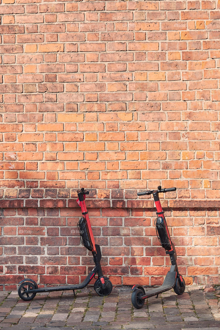 Two electric scooters left in the street ready to hire by using rent service on smartphone. Copy space in the top. Candid people, real moments, authentic situations