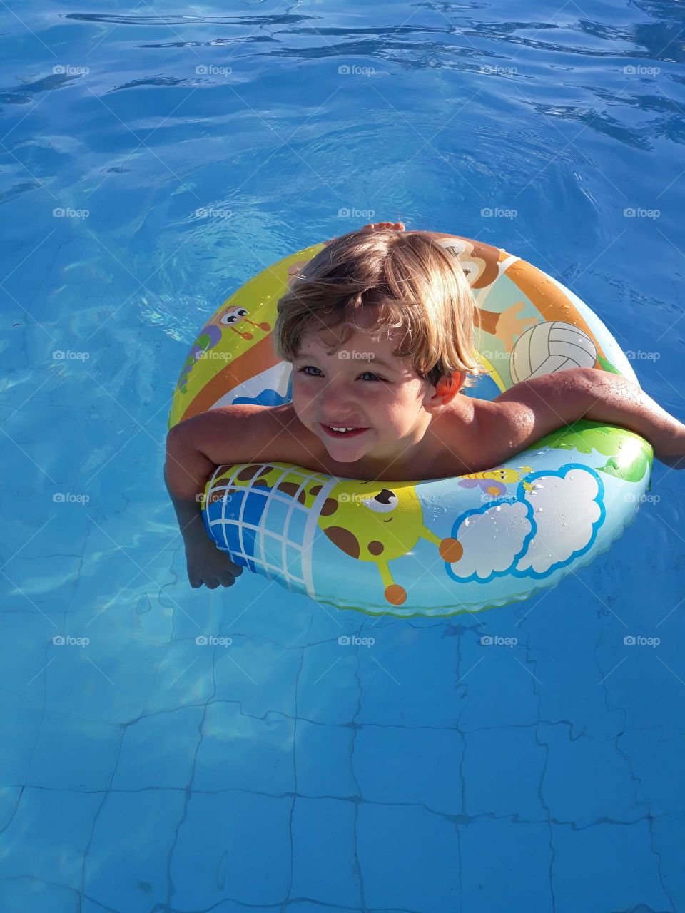 blonde child on the float smiling in the pool