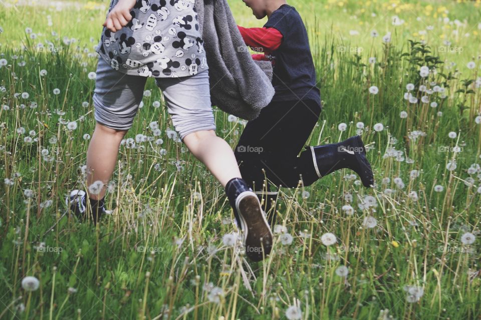 Children running in a field full of dandelions