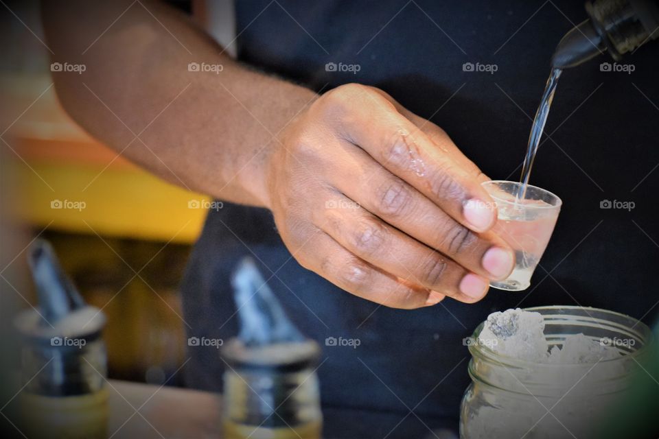 Bartender pouring drink in small glass