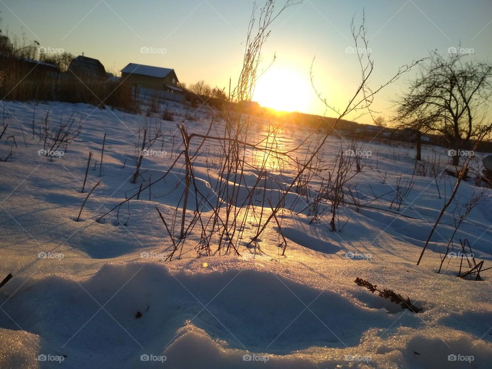 photo of snowy landskape at sunset. Snow reflects sunlight. Photo is in warm photos