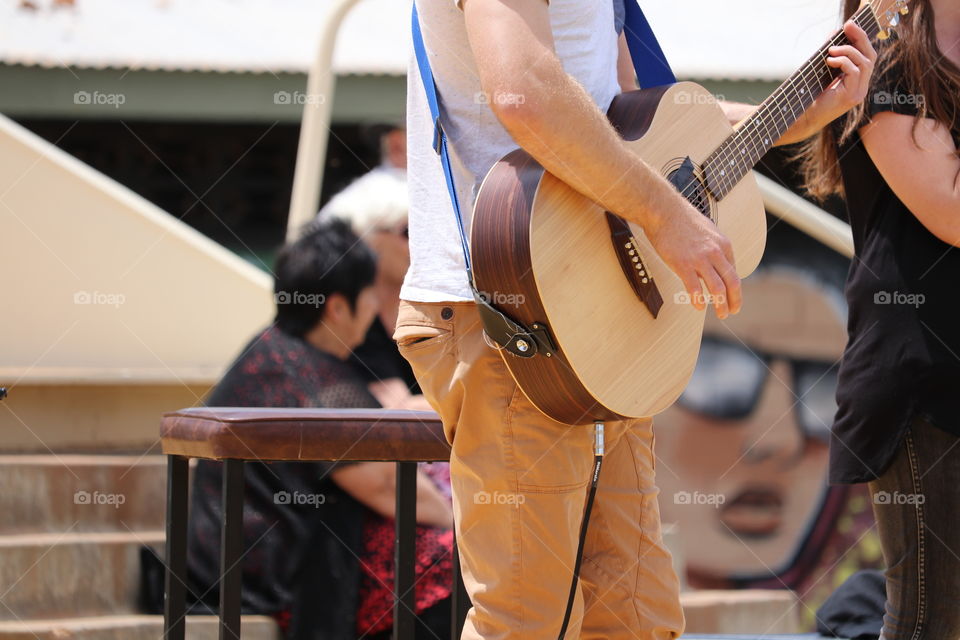 Male performer with guitar on outdoor stage performing 
