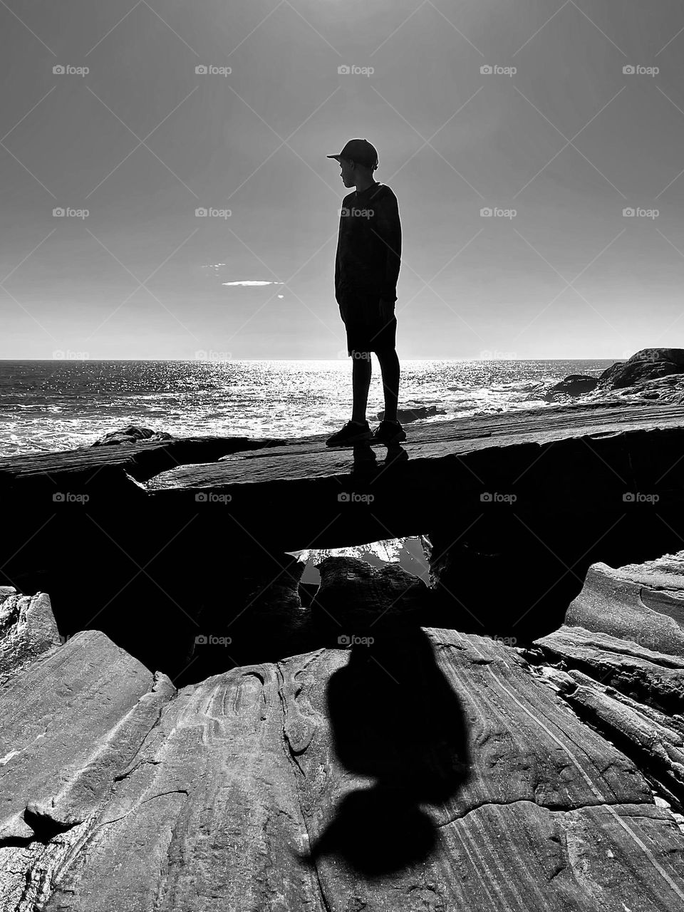 “Larger Than Life”.   A boy stands at the ocean”s edge as the sun casts a dramatic shadow.