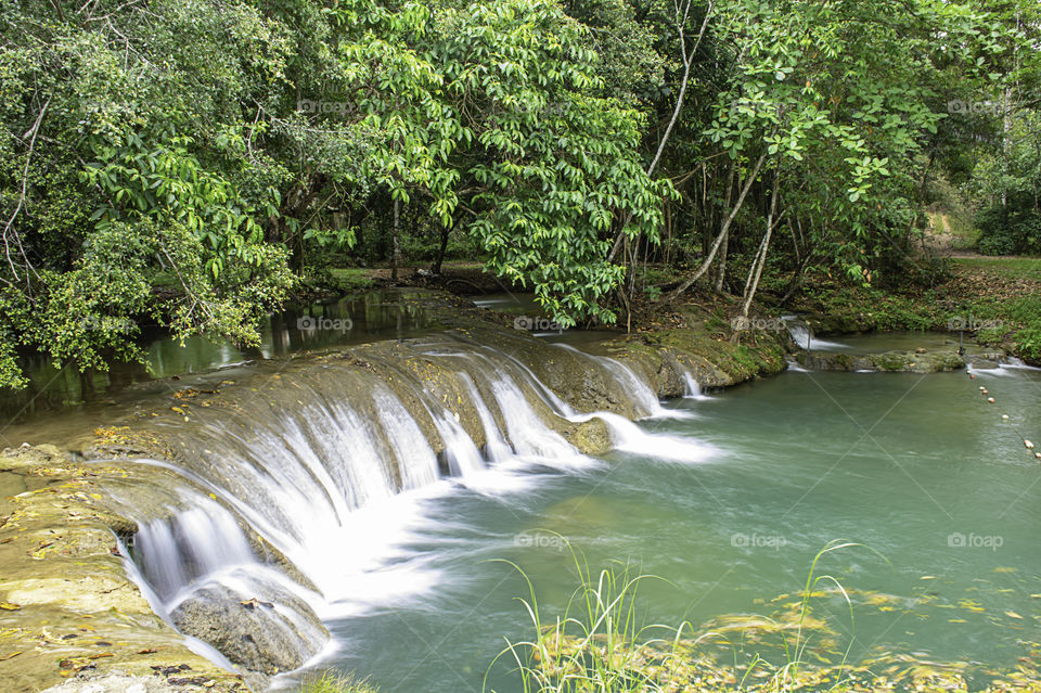 The water flowing over rocks and trees down a waterfall at Kapao waterfall National Park ,Chumphon in Thailand.