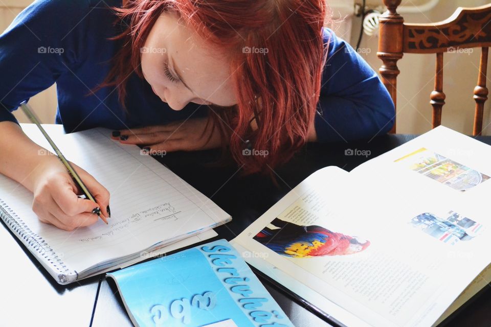 Small girl writing on notebook with pencil