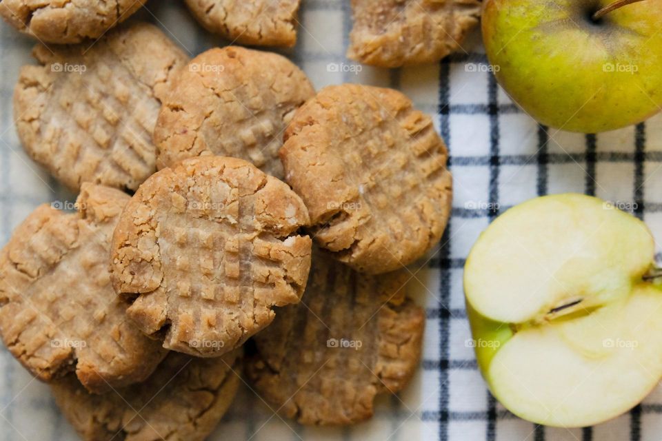 Close up of American peanut butter cookies with cut apple on the checkered napkin