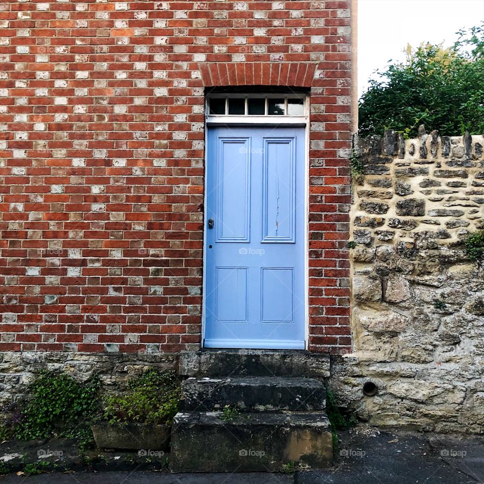 Blue doorway on a red brick wall with steps 