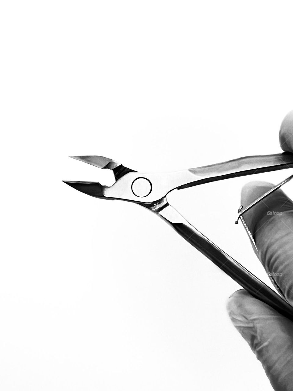 Hand in glove with manicure nippers on white background