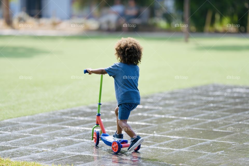 lovely child rides a scooter in the park