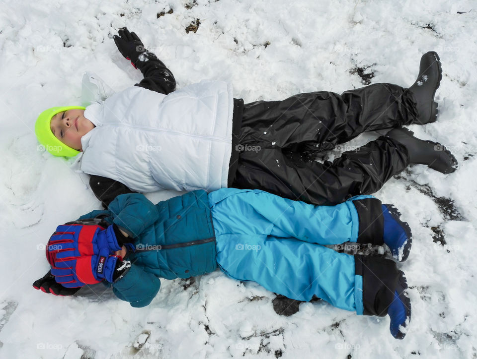 two children laying in the snow