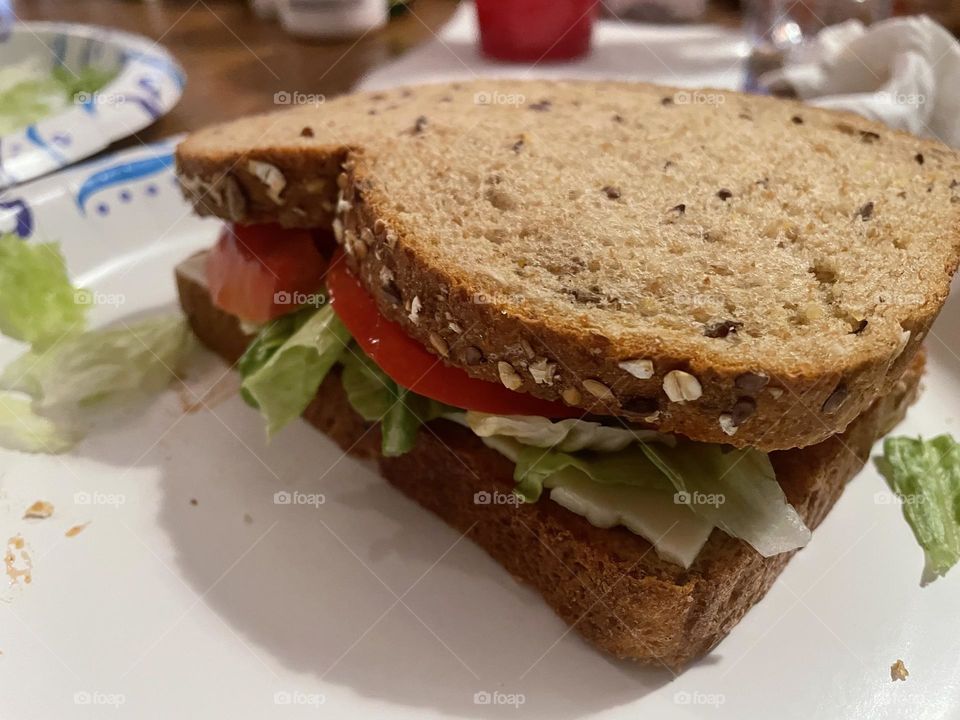 Tomato sandwich with lettuce, mayonnaise, and cheese on whole wheat bread