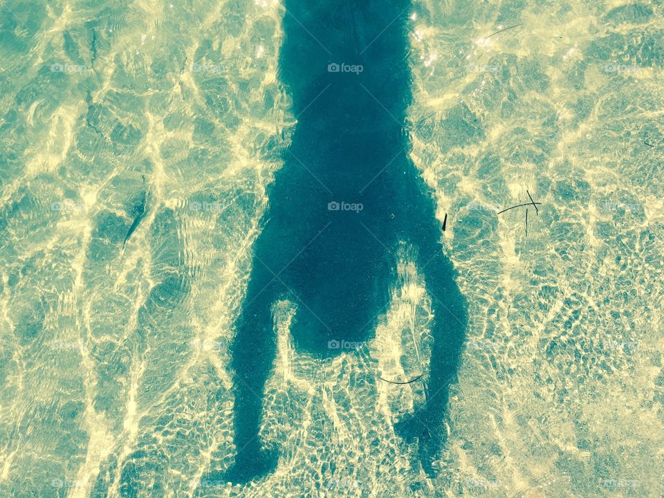 Shadow with hands up in the water