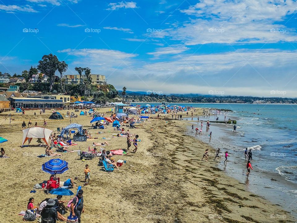 Summertime on the beach in Capitola by the Sea in California on a warm summer afternoon with the surf and people enjoying their vacation