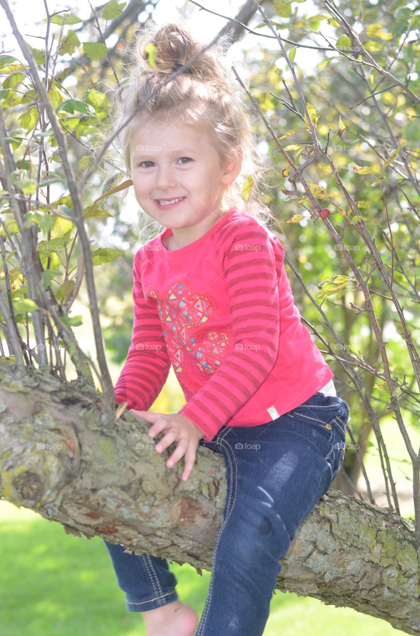 Cute girl sitting on tree trunk