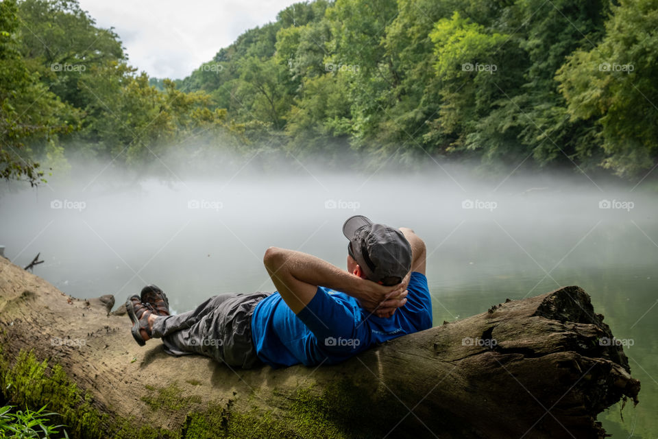 Foap, Landscapes of 2019: An outdoor enthusiast chills on a log on the banks of a foggy Elk River near Winchester, Tennessee. 