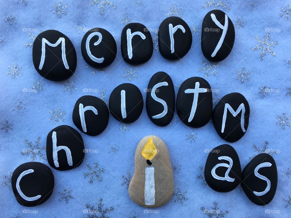 Merry Christmas with black painted stones over white carpet