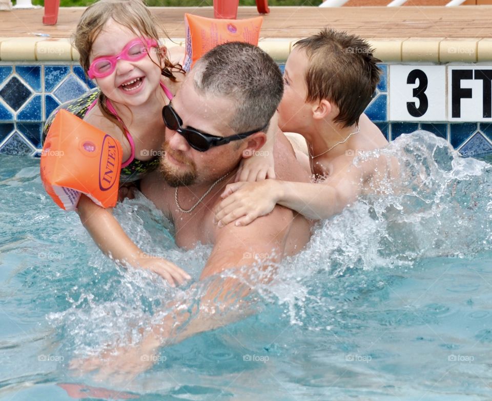 Spending a vacation with family, father with daughter and step-son swimming in a pool at Siesta Key Florida